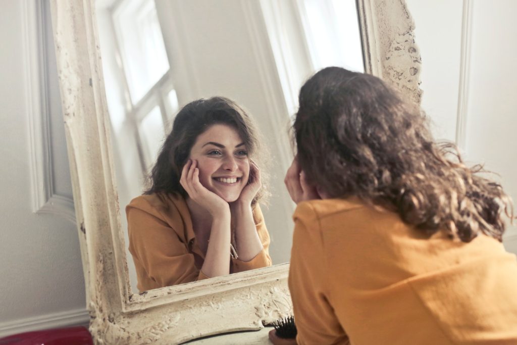 A happy lady smiling and looking at herself in the mirror